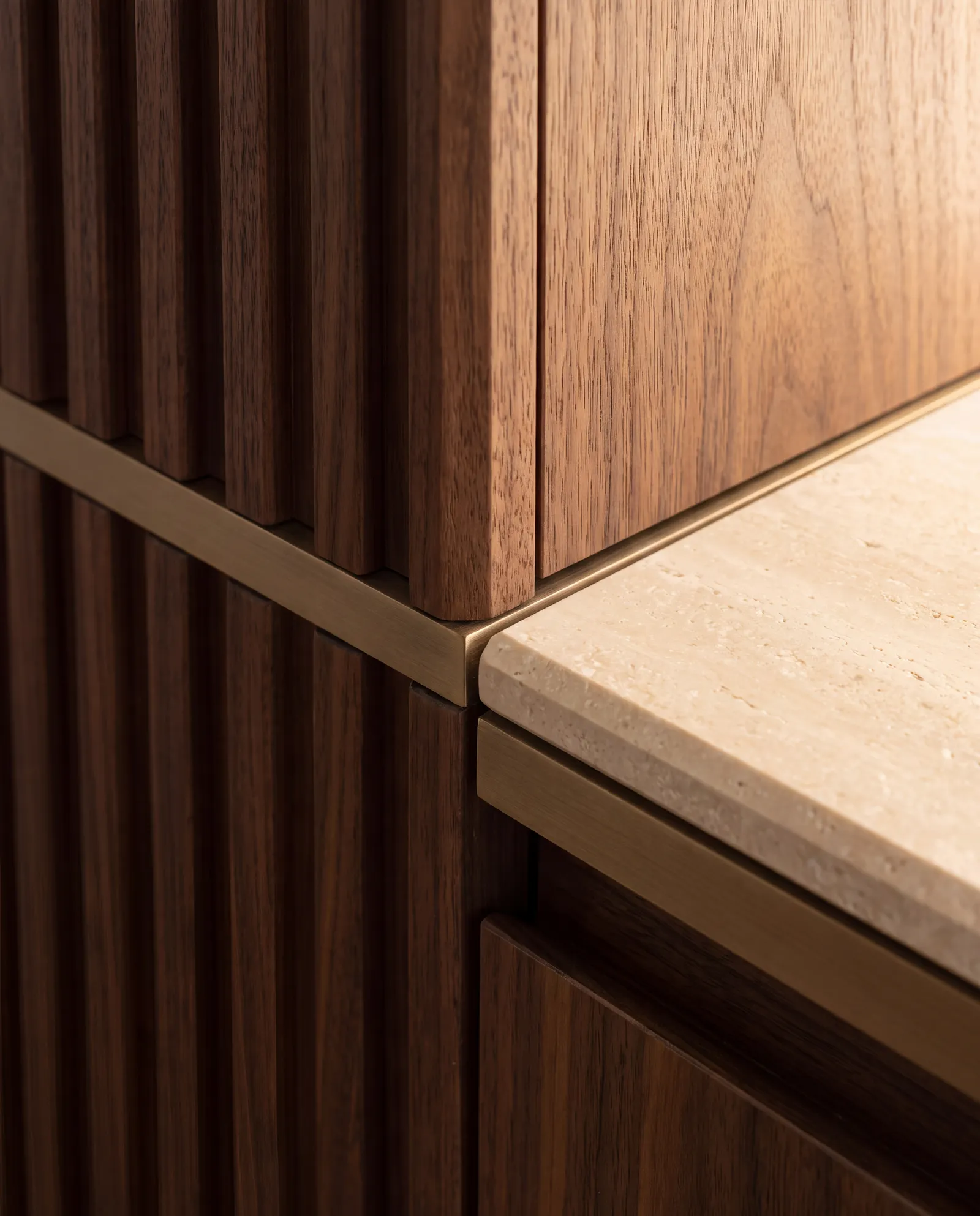 Close-up of walnut, travertine and bronze joinery