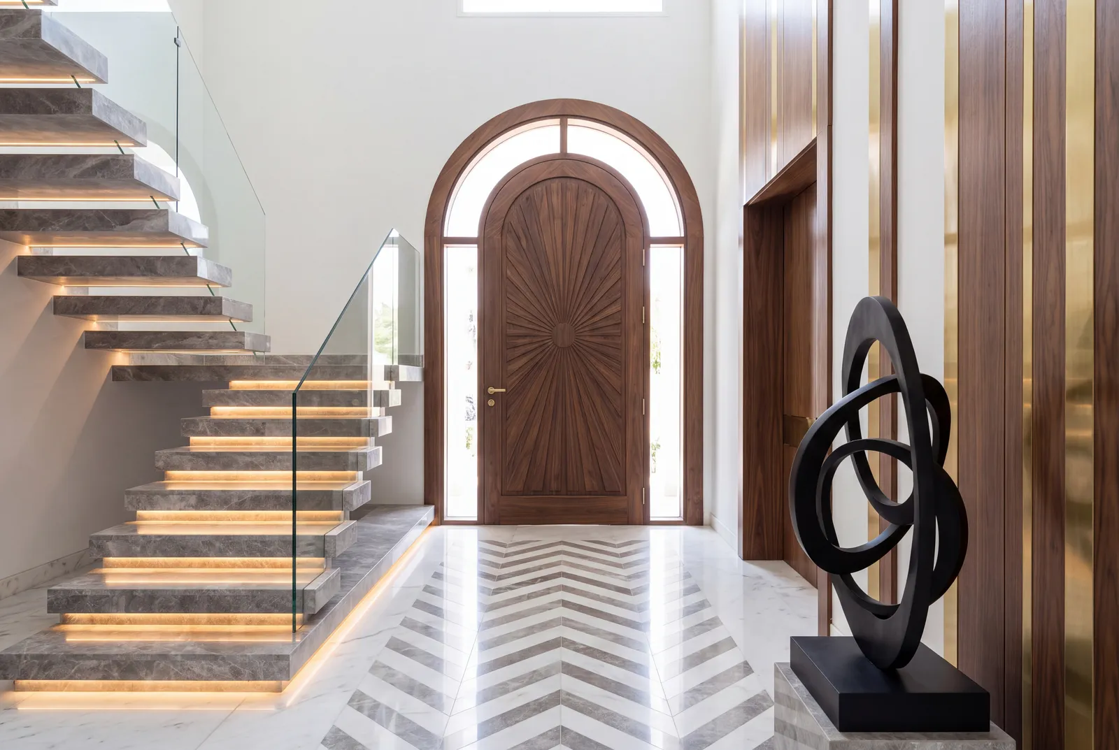 Floating marble staircase with a walnut arched door